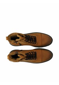 Hellbraune Leder-Stiefeletten mit schwarzen Schnürsenkeln, einem mit Fell gefütterten Innenraum und seitlichem Reißverschluss. Sie haben eine runde Zehenform und eine strukturierte Sohle für besseren Halt.