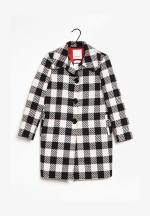 Károvaný kabát s černým, bílým a červeným vzorem, s klasickým límcem, pěti černými knoflíky a texturovanou látkou. Visí na černém háčku.