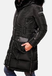 Černý prošívaný kabát s kapucí lemovanou umělou kožešinou, zapínáním na zip a knoflíky, několika kapsami, prošívanou texturou a elegantním designem.