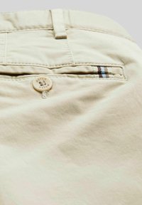 Beige Baumwollhose mit einer Gesäßtasche, die einen Knopf hat, und einem gestreiften Stoffakzent in Braun und Blau. Glatte Textur und maßgeschneiderte Passform.