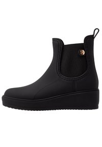 Bottes de cheville en caoutchouc noir au design élégant, avec des panneaux latéraux élastiques, un bout arrondi et un talon compensé, arborant un accent de logo métallisé.