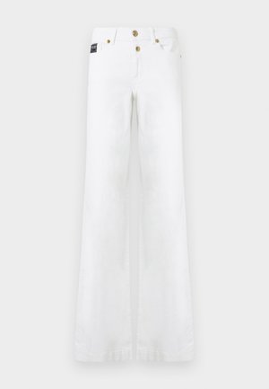 Bela široke kavbojke z žepi spredaj, zankami za pas in zlatimi gumbi na enobarvnem ozadju.