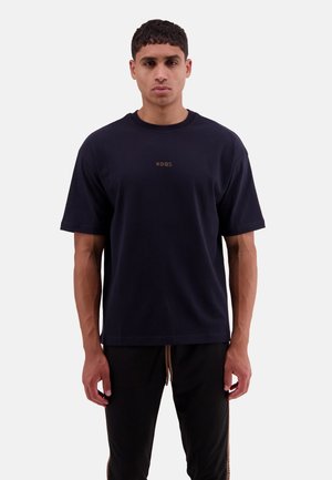 Dunkelblauses Baumwoll-T-Shirt mit Rundhalsausschnitt und kurzen Ärmeln. Verfügt über dezente goldene Markenlogos auf der Brust. Einfaches, lockeres Design.