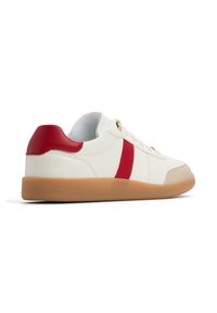 Sneaker bianco con una striscia di accento rossa e un linguetta sul tallone, dotato di una suola in gomma marrone chiaro e lacci bianchi. Tessuto in pelle liscia.