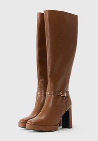 Botas de cuero marrón hasta la rodilla con un acabado brillante, que presentan una puntera cuadrada, un tacón alto y grueso, y una correa decorativa con detalle de hebilla.
