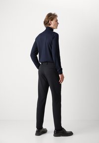 Mornarska rolka, crne krojene hlače, elegantne crne cipele. Glatka tekstura, uski dizajn, moderna silueta, minimalni naglasci.