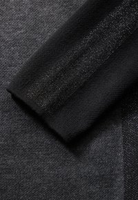 Maglione a maglia in grigio scuro e nero, con una superficie leggermente strutturata e un accento di filo metallico che corre lungo un bordo.