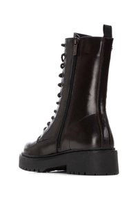 Botín de charol negro hasta el tobillo con cordones en la parte delantera, cremallera lateral, suela gruesa y banda de rodadura texturizada. Presenta un lazo en el talón.