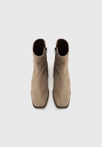 Semskede ankelstøvler i lys brun med firkantet tådesign, med sidelommer og en glatt tekstur. Minimalistisk stil uten synlige mønstre.