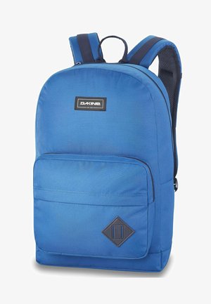 Blauer Rucksack aus strapazierfähigem Stoff, mit einer Vorderfach, verstellbaren Trägern und einem Diamantakzent an der unteren Vorderseite. Glatte Textur.