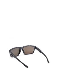 Sunglasses med en svart plastbåge, rektangulära linser och brunt tonade linser. Har texturerade accenter på bågen och smala, böjda glasögonbågar.