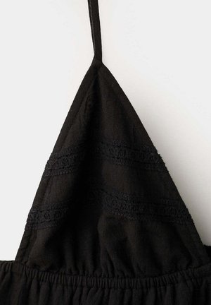 Czarny materiałowy top w kształcie trójkąta z cienkim paskiem na ramię i poziomym koronkowym detalem nad marszczonym elastycznym szwem.
