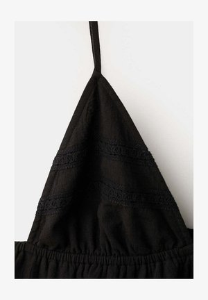 Schwarzes Stoff-Dreieck-Top mit dünnem Schulterträger und horizontalem Spitzen-Detail über der gerafften elastischen Naht.