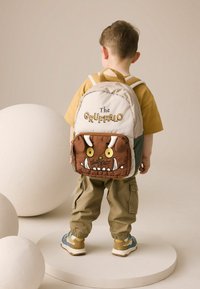 Brun plyschryggsäck med karaktären "The Gruffalo", med vita betar, gula ögon och grön näsa. Tyget är mjukt och har justerbara axelremmar.