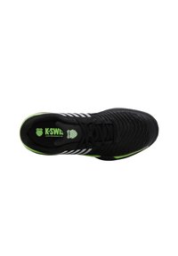 Zapatilla deportiva negra con un upper texturizado, acentos en blanco y verde, y una suela acolchada. Presenta un diseño de cordones y una marca en la plantilla.