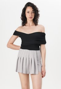 Čierny off-shoulder top s nariasenou textúrou, skombinovaný s svetlo šedými plisovanými šortkami. Jednoduchý, priliehavý dizajn s čistými líniami a bez viditeľných vzorov.