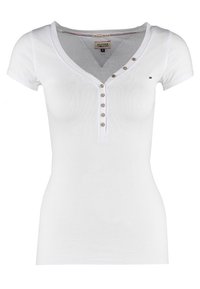 Vit ribbad kortärmad skjorta med V-halsringning och fem pärlliknande knappar fram. Diskret logotypdetalj på bröstet.