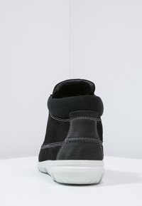 Černé semišové vysoké tenisky s síťovaným límcem, bílou gumovou podráżkou, viditelným šitím a elegantním designem. Pohled ukazuje zadní část boty.