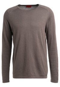 Maglietta a maniche lunghe con collo a giro in un colore marrone tenue, realizzata in tessuto a maglia con una texture morbida. Presenta cuciture a contrasto e un'etichetta al colletto.