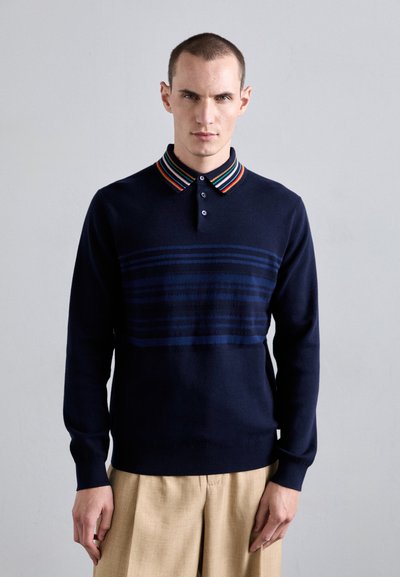Marineblå sweater med en stribet krave, der har røde, blå og grønne accenter. Blød tekstur, struktureret pasform og knap-lukning.