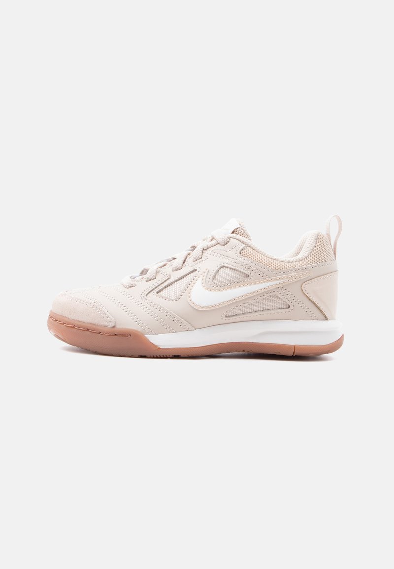 Ανοιχτό μπεζ αθλητικό παπούτσι Nike με λευκό λογότυπο swoosh, επάνω μέρος από πλέγμα και συνθετικό υλικό, λευκή ενδιάμεση σόλα και ανοιχτό καφέ λαστιχένια σόλα.