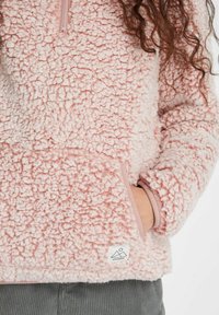 Rosa Fleece-Pullover mit einem Reißverschluss am Kragen, strukturierten Oberflächen, elastischen Bündchen und einem Logopatch am Saum. Warmer und weicher Stoff.