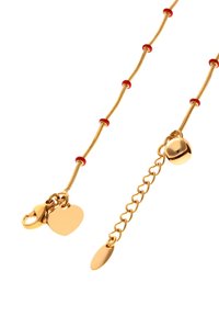 Zlatý řetízek s červenými korálky, vybavený karabinkovým zapínáním, srdcovým přívěskem a nastavitelným prodlužovacím řetízkem s oválným štítkem.