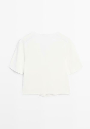 Weißes, kurzärmeliges, bauchfreies Shirt mit rundem Halsausschnitt und einem dezenten Schlitz am Saum auf der Rückseite, vor weißem Hintergrund dargestellt.