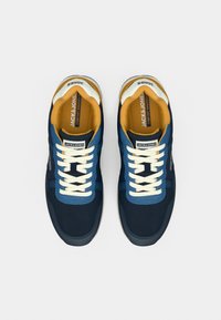 Μπλε αθλητικά παπούτσια με εκρού κορδόνια, κίτρινη εσωτερική επένδυση και υφασμάτινα πάνελ με υφή. Διαθέτουν λογότυπο στη γλώσσα και στο πλάι. Λαστιχένια σόλα.