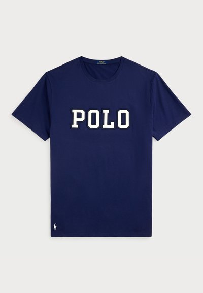 Navy blue cotton t-shirt with short sleeves featuring a large white "POLO" logo in a bold font and a small logo detail on the hem.