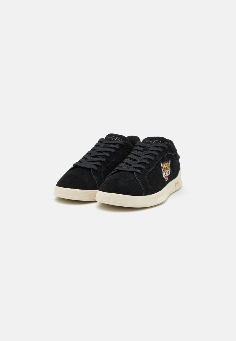Schwarze Wildleder-Sneaker mit niedrigem Profil, ausgestattet mit schwarzen Schnürsenkeln, einer beigen Gummisohle und einem gestickten Tiger-Motiv an der Seite.