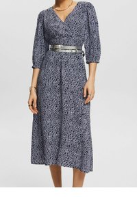 Námořnické šaty s bílým abstraktním vzorem, výstřih do V, rukávy tříčtvrteční délky, zúžený pas s kovovým páskem a splývavá sukně ve tvaru A.