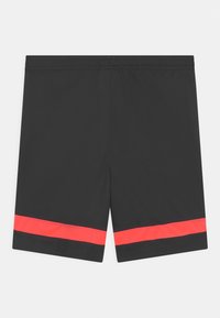 Svart elastisk midjeshorts med ett horisontellt, ljust rött rand nära fållen på varje ben, visas mot en vit bakgrund.