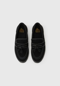 Czarne zamszowe mokasyny z detalem w postaci chwostów, kontrastującym białym przeszyciem oraz gumową podeszwą. Wyposażone w wyściełaną wkładkę dla zapewnienia wygody.