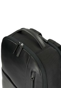 Zaino nero con corpo in pelle texture, pannelli in rete, chiusure a doppia cerniera e maniglia superiore imbottita per il comfort.