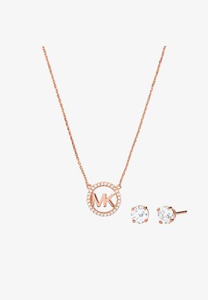 Collar de oro rosa con un colgante circular que presenta las iniciales "MK" rodeadas de cristales brillantes, acompañado de pendientes de botón a juego.