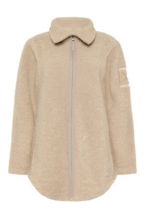 Beżowa kurtka polarowa na całym zamek z wysokim kołnierzem, długimi rękawami, teksturowaną tkaniną i małą naszywką na lewym górnym ramieniu.