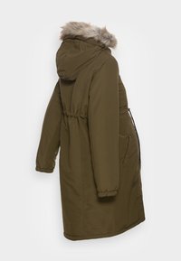 Parka matelassée vert olive avec capuche doublée de fausse fourrure, taille cintrée, poignets élastiques et poches latérales zippées. Texture lisse, coupe mi-longue.