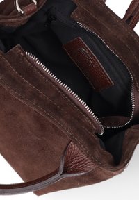 Borsa tote in suede marrone con dettagli in pelle liscia, chiusura con zip e rivestimento in tessuto; presenta manici robusti e dettagli texturizzati.