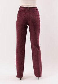 Pantaloni color bordeaux realizzati in tessuto strutturato, con vita alta e due tasche posteriori. Design a gamba dritta con una lieve lucentezza.
