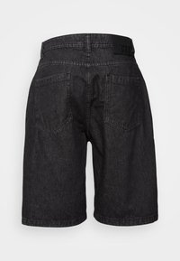Shorts en denim noir avec une taille mi-haute, deux poches arrière et un patch en cuir noir avec logo. Style droit et couture minimale.