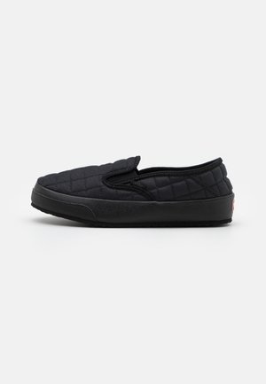 Sort quiltet slip-on sko med gummisål og lav profil, vist fra siden mod en ensfarvet baggrund.