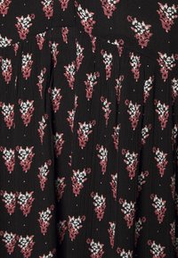 Musta kangas kukkakuviolla, jossa on valkoisia ja vaaleanpunaisia kukkia. Suunnitelmassa on laskoksia ja pieniä valkoisia pisteitä yksityiskohtina.