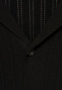 Black knitted cardigan with a textured pattern and ribbed fabric, featuring a pointed collar and a single black button closure.