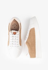 Zapatillas blancas con paneles de tela trenzada en tono marrón, cordones planos y suela de goma texturizada. El interior cuenta con una etiqueta de cuero de la marca.