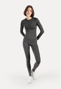 Sort atletisk sæt bestående af en langærmet top og leggings lavet af strækbart stof med teksturerede detaljer og en tætsiddende pasform.