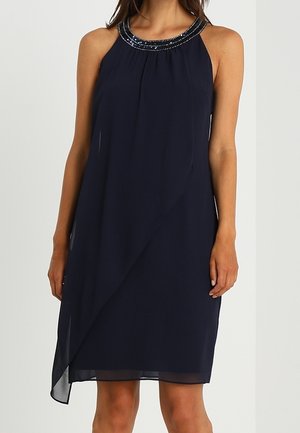 Granatowa sukienka bez rękawów z koralikowym, wiązanym na szyi dekoltem oraz asymetryczną warstwą zwiewnego szyfonu sięgającą nieco poniżej kolana.