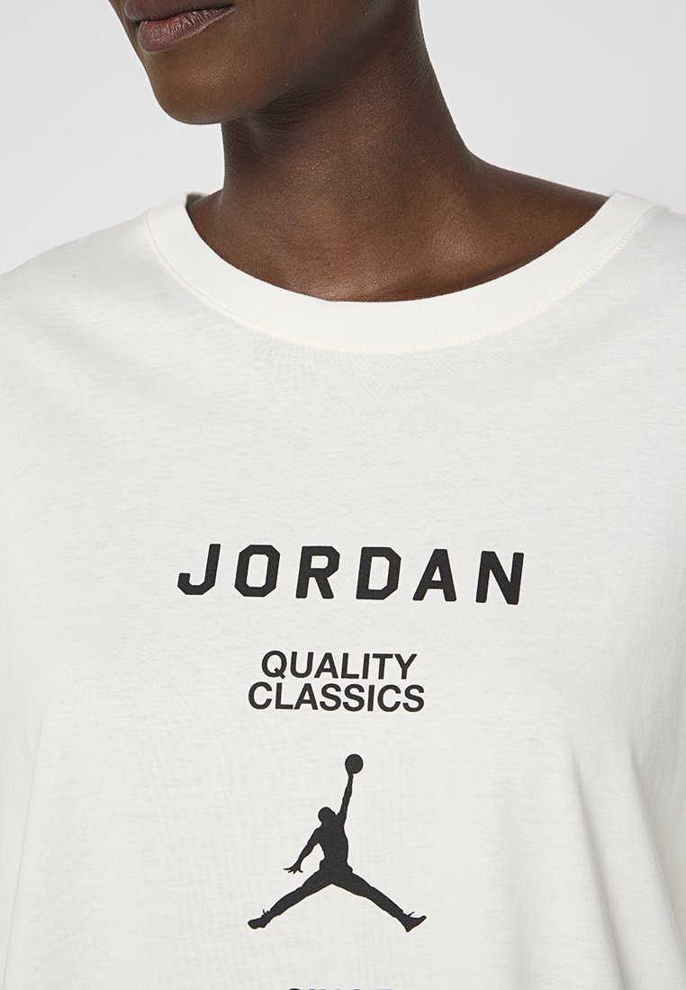 Biała bawełniana koszulka z czarnym napisem "JORDAN" i pod nim napisem "QUALITY CLASSICS", z czarnym konturem logo Jordana na środku.