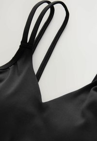 Top bikini nero con spalline sottili e regolabili e una consistenza liscia. Presenta un design con scollatura a V profonda e uno stile minimalista.