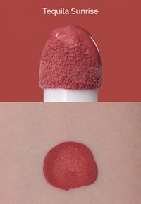 Flüssiger Lippenstift mit der Aufschrift "Tequila Sunrise", korallfarbener Ton mit einem weichen, samtigen Applikator. Swatch zeigt eine glatte, gleichmäßige Schicht auf der Haut.